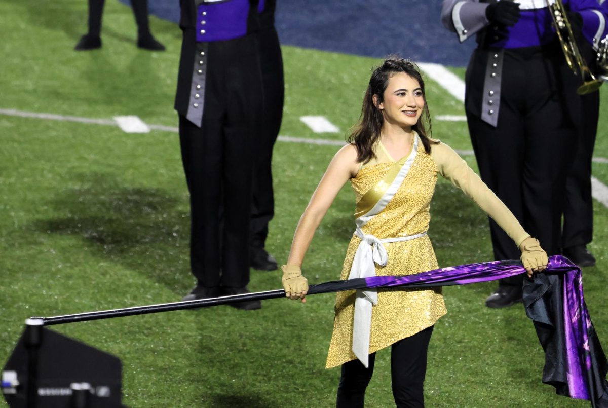 SWEEPSTAKES & SMILES.  Leading the color guard, capitan junior Valentina Romo performs with the band at UIL. 