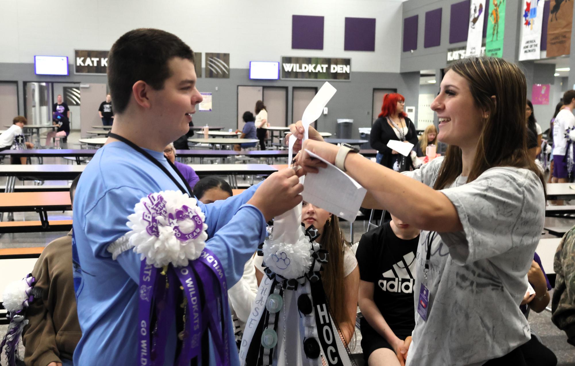 HOMECOMING HAND-OFF. Adding another garter to his collection, freshman Chase Duvall takes the garter junior Tatum Authement ade for him in advanced floral design class.