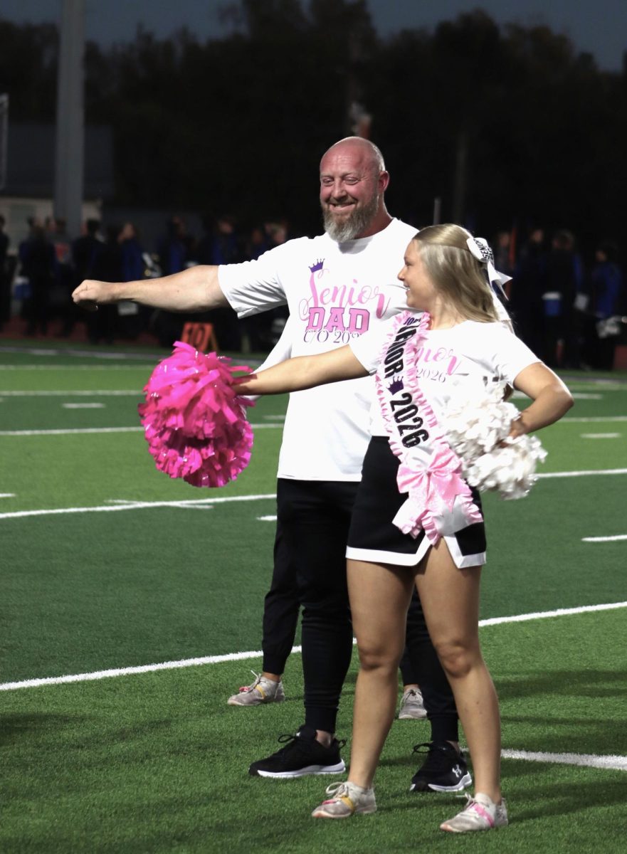 WATCH ME. Showing her dad Josh Sager how it is done, senior Jordynn Sager dances to the school song during pregame activities. Each senior got to cheer with their dad during the pregame and first quarter. 
