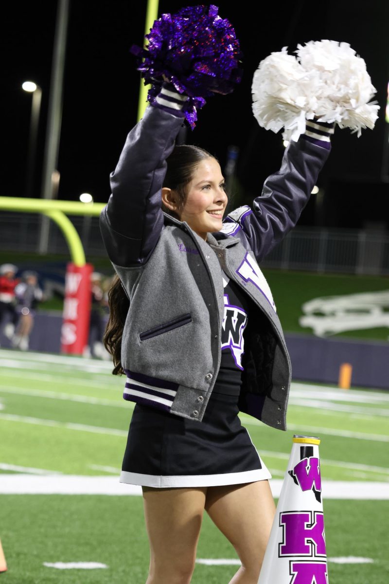 CHEERING ON THE KATS. Facing the Wildkat fans, junior Lauren Stafford motivates the crowd to get loud for the team.