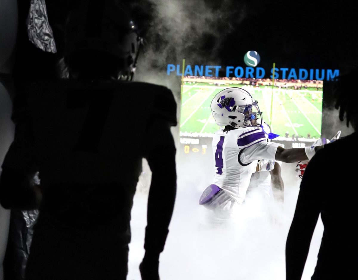 THROUGH THE FOG. Followed by his teammates, junior A'Majai Friend run through the tunnel into Planet Ford Stadium. 