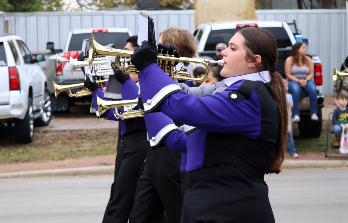 JOY TO THE WORLD. At the Willis Christmas parade with the theme Oh What Fun, sophomore Chloe Corrales marches with the trumpet section while playing Christmas music to entertain the crowd. The band was named the outstanding marching entry at the parade. photo by Ryder Sciba