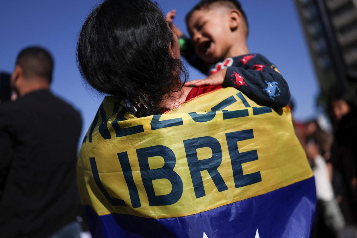 A woman, with a flag on her back reading "Freedom", lifts her son, after U.S. President Donald Trump said that the U.S. attacked Venezuela and deposed its President Nicolas Maduro, in Santiago, Chile January 3, 2026. REUTERS/Pablo Sanhueza