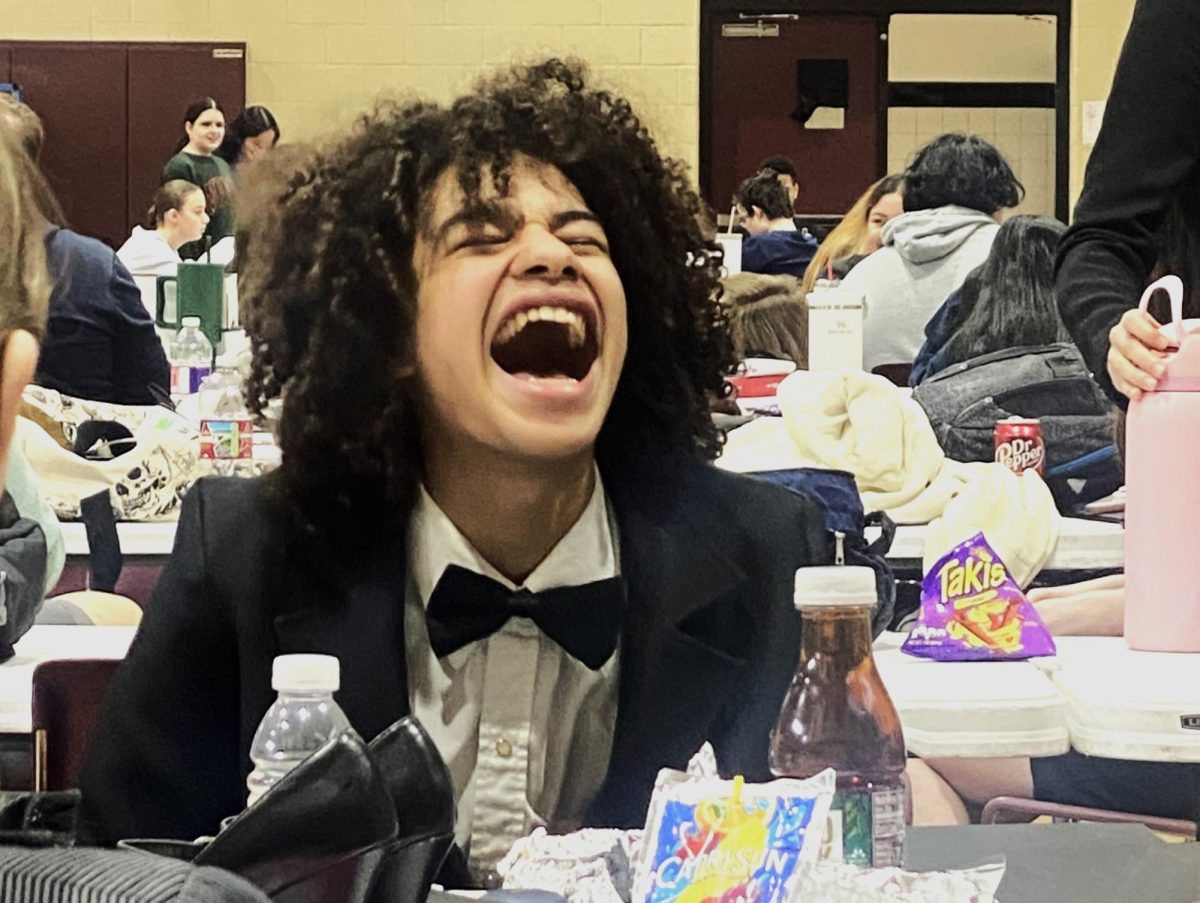 ALWAYS ENTERTAINING. After the first round of competition, sophomore Chege Wechage tells a story to his teammates. Wechege placed first in the poetry competition at the New Waverly meet.