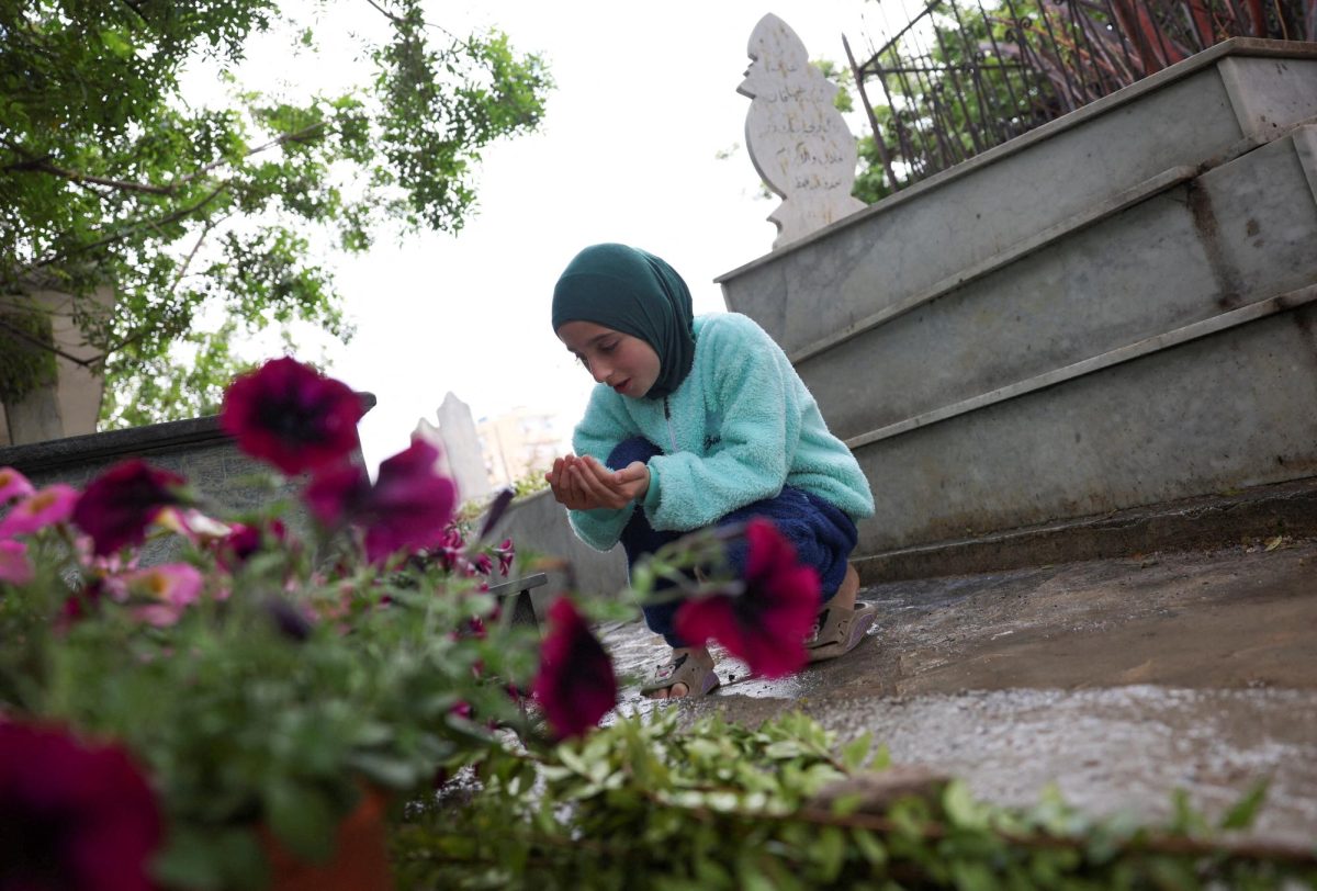 A displaced girl from Tyre prays in front of a grave at a Shi'ite cemetery, on the day of Eid al-Fitr, marking the end of the Muslim holy fasting month of Ramadan, following an escalation between Hezbollah and Israel amid the U.S.-Israeli conflict with Iran, in Sidon, Lebanon, March 20, 2026. REUTERS/Amr Abdallah Dalsh